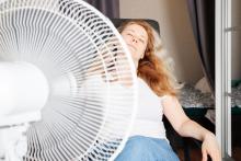 Woman sitting in front of a fan inside home