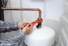 worker with tool in hand is repairing a boiler